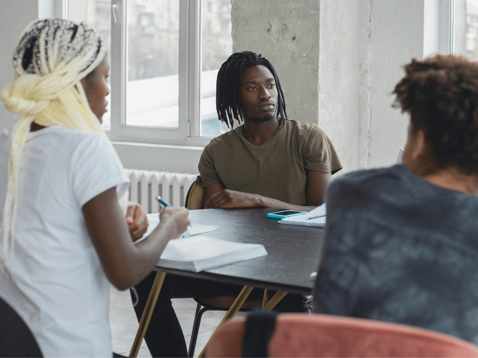 drei DaZ-Schüler*innen sitzen am Tisch im Klassenzimmer und lernen sich kennen