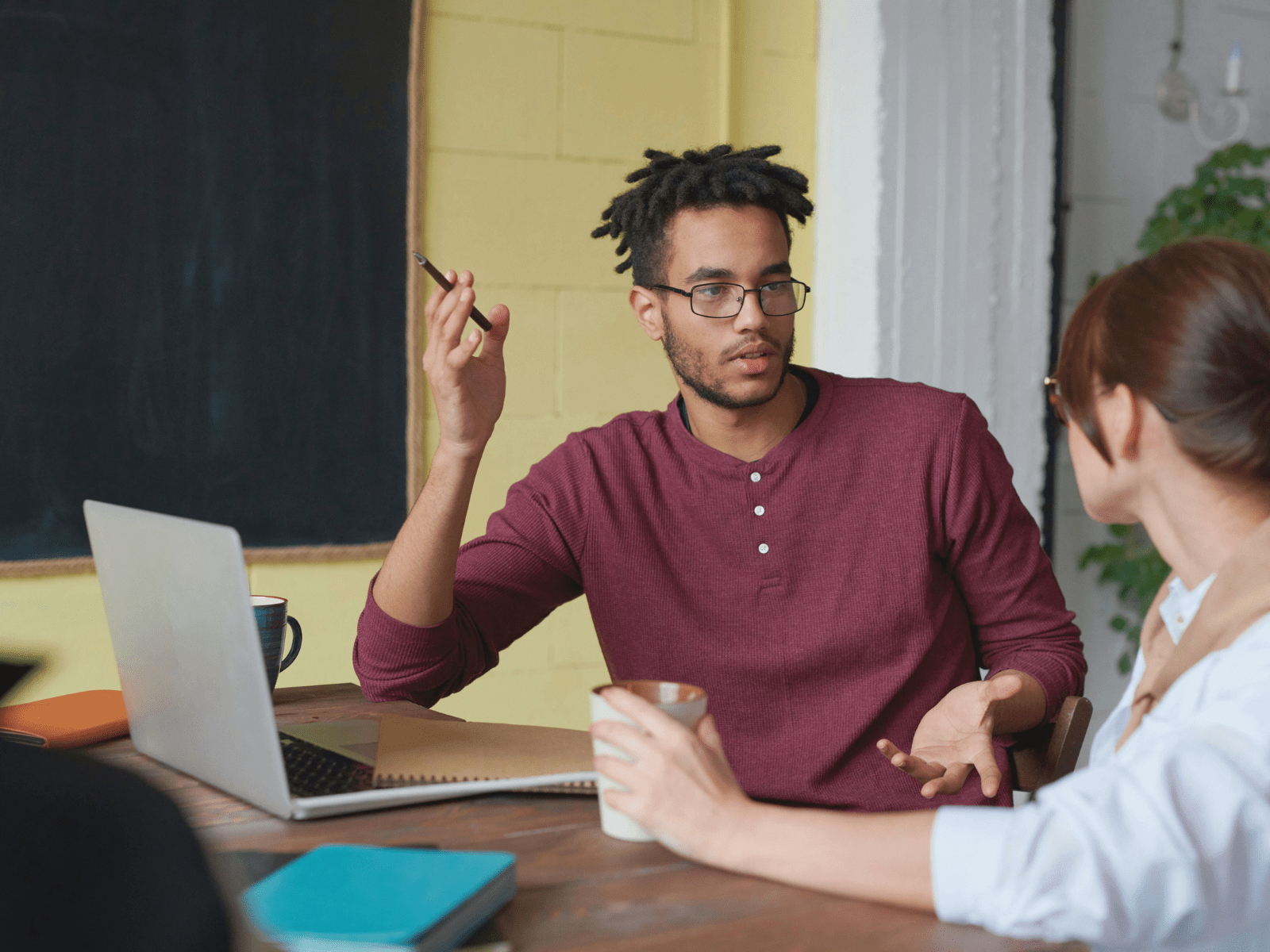 eine Lehrkraft erklärt einer anderen Person etwas an einem Tisch im Klassenraum