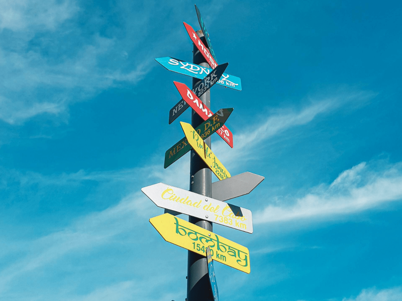 in verschiedenen Sprachen beschriftete Schilder zeigen in verschiedene Richtungen mit dem Himmel im Hintergrund