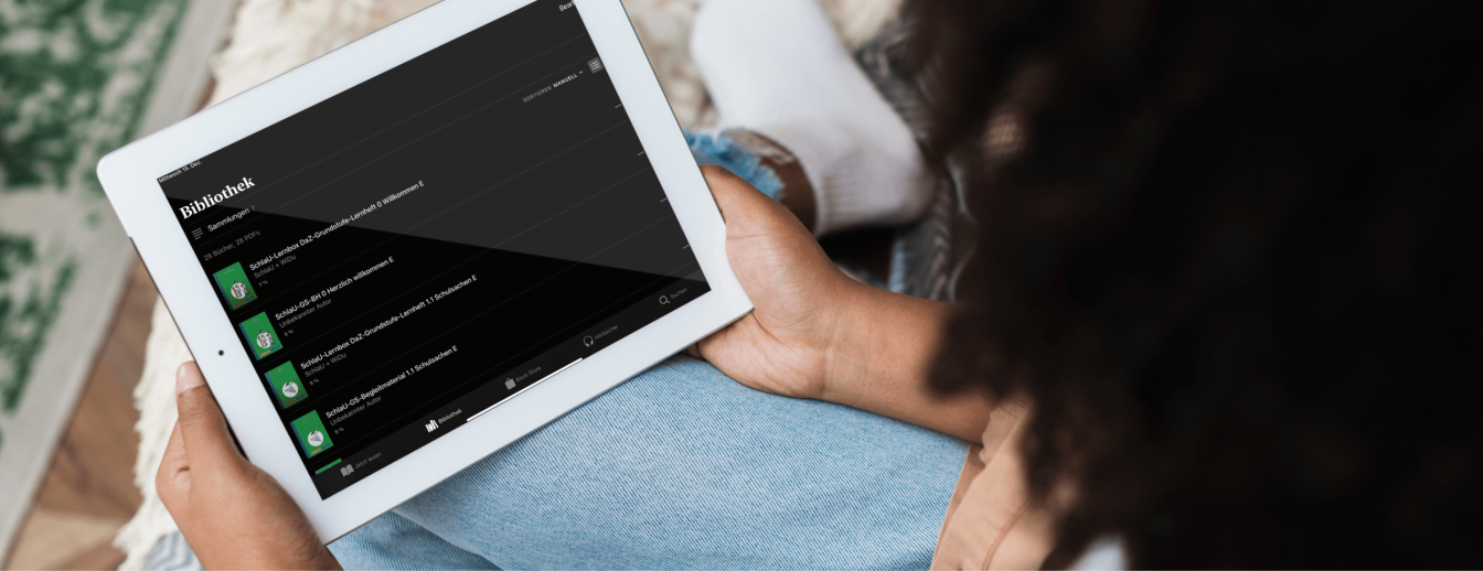 eine Person hat ein Tablet in der Hand und sieht sich die mehrsprachigen E-Books von SchlaU an