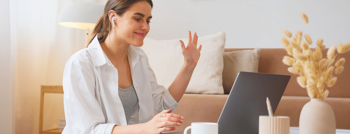 Lehrkraft winkt vor dem Laptop während einer digitalen Fortbildung von SchlaU in die Kamera